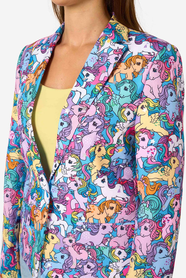 Woman wearing a colorful patterned My Little Pony blazer on a light background. Chest close-up.
