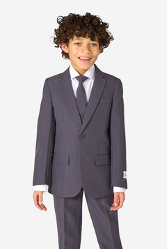 Kid wearing a stylish charcoal colored grey suit with a white dress shirt, smiling confidently. Perfect formal outfit for boys' special occasions, weddings, and parties.