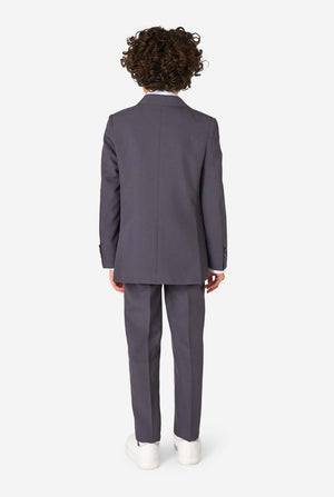 Kid wearing a stylish charcoal colored grey suit with a white dress shirt, smiling confidently. Perfect formal outfit for boys' special occasions, weddings, and parties. View from the back.