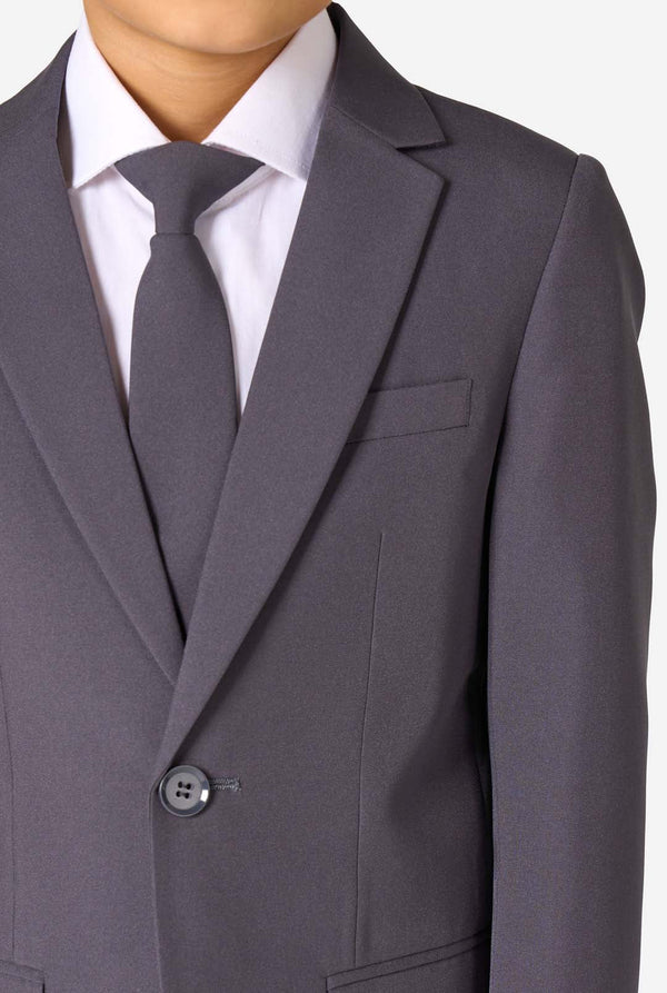 Kid wearing a stylish charcoal colored grey suit with a white dress shirt, smiling confidently. Perfect formal outfit for boys' special occasions, weddings, and parties. Chest close-up.