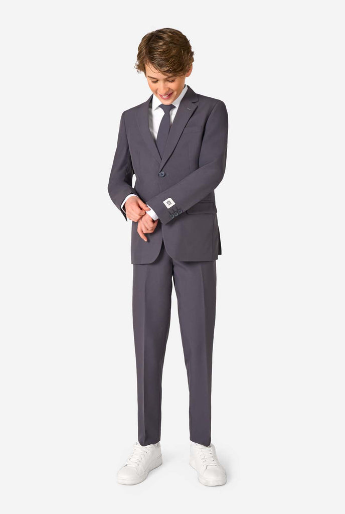 Teen boy wearing a stylish charcoal colored grey suit with a white dress shirt, smiling confidently. Perfect formal outfit for boys' special occasions, weddings, and parties. Full body image.
