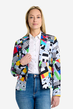 Woman wearing a colorful patterned blazer over a white shirt and blue jeans on a white background
