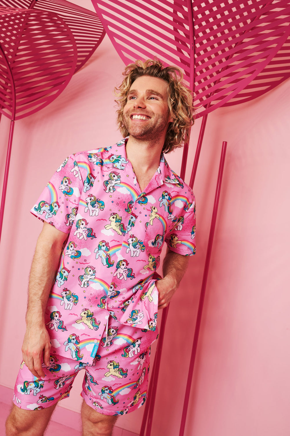 Man wearing a pink My Little Pony summer combo against a pink background with decorative leaves.