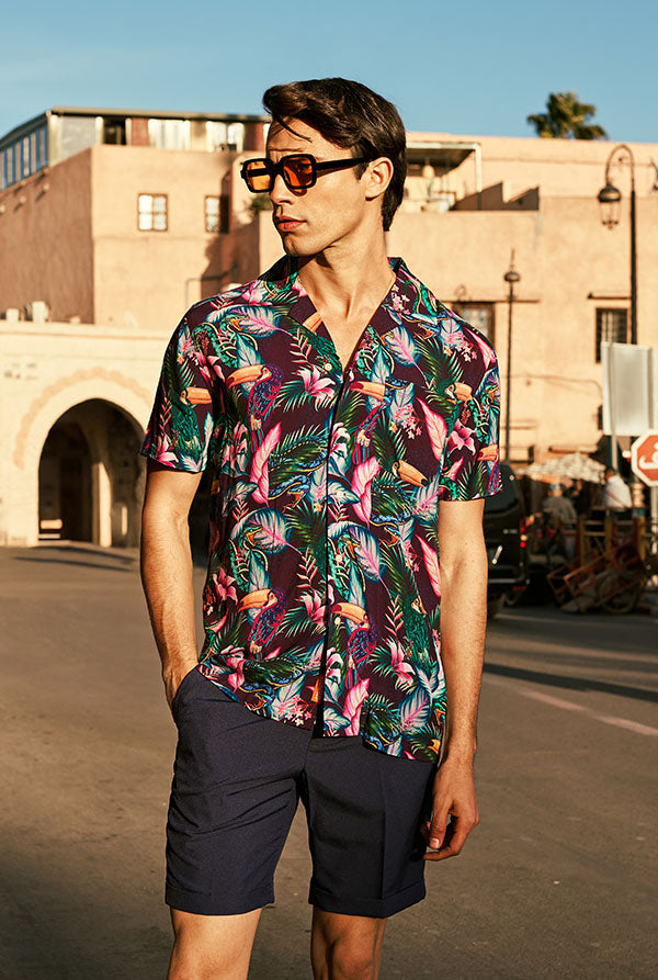 Man wearing a colorful floral shirt and sunglasses on a street.