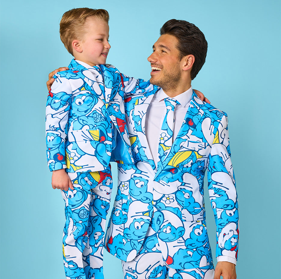 This is an image with a light blue background, and a man and kid wearing a suit with an all-over Smurf suit. They are looking at each other.