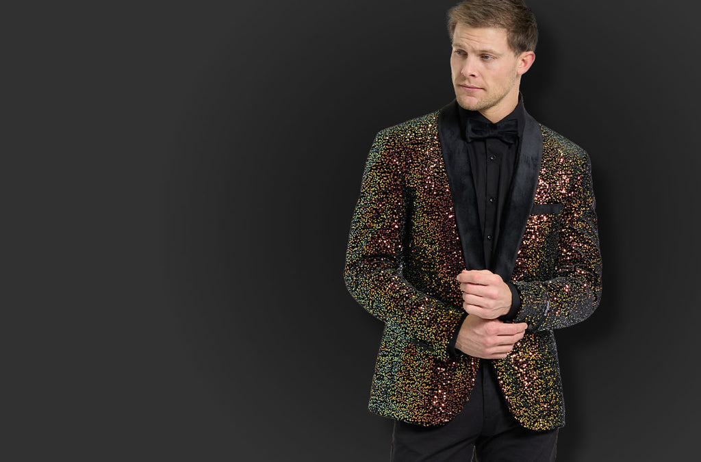 Man standing in front of black background wearing a mens blazer covered with golden shimmering sequins and a black velvet shawl lapel.