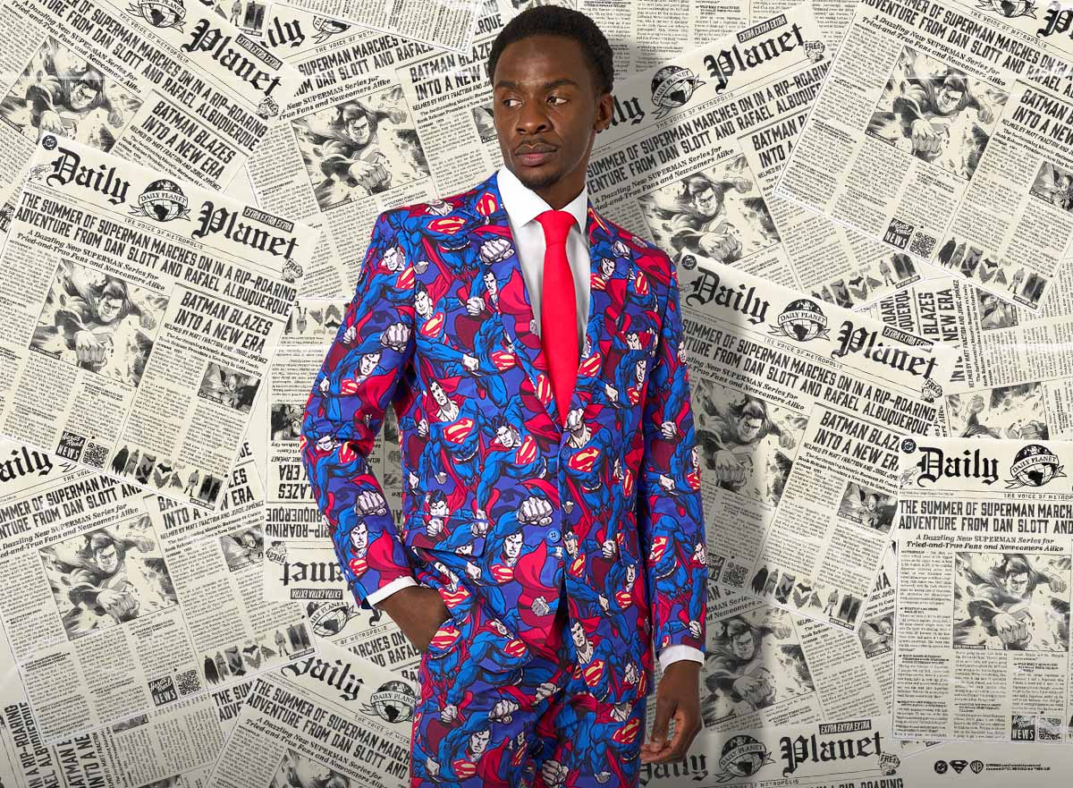 A men wearing a superman themed suit with a red tie and newspapers as a background