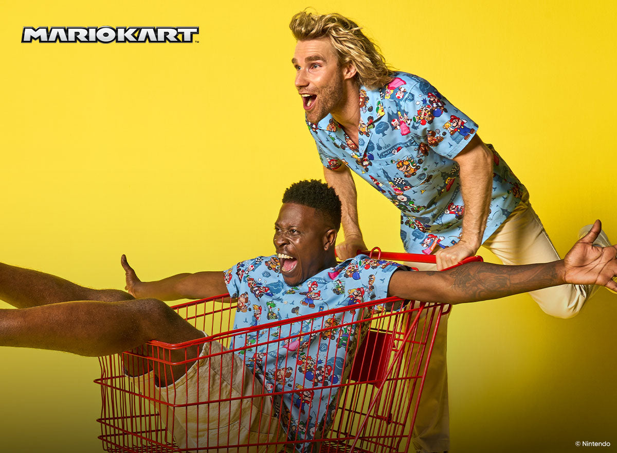Image with yellow back ground and two men wearing blue Hawaiian with Mario Kart characters. One man in a shopping cart and the other pushing the cart.