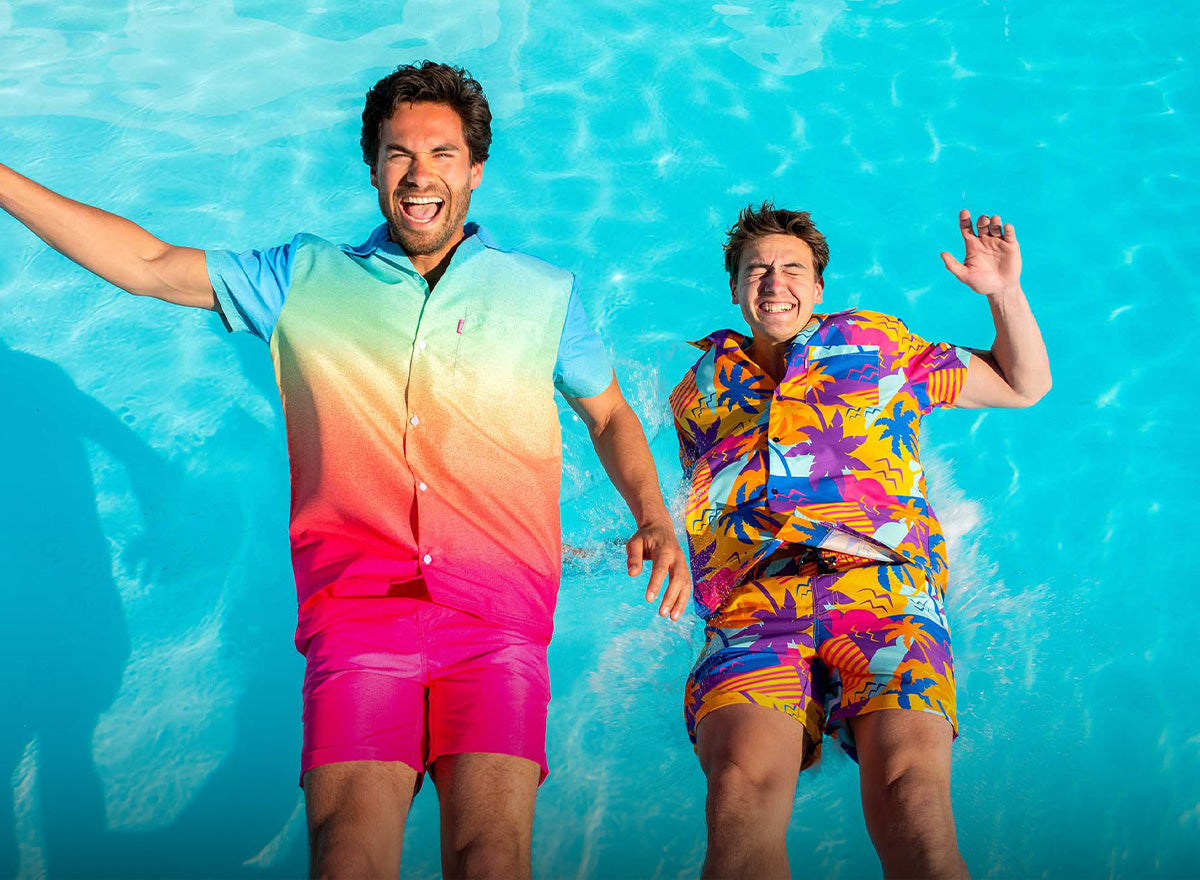 Two men falling in the swimming pool wearing colorful summer sets from OppoSuits.
