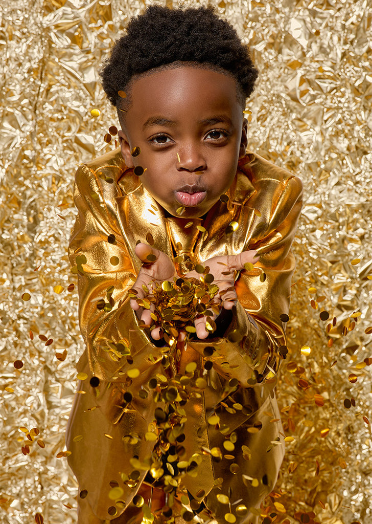 Kid wearing golden suits and trowing golden confetti. Image background is golden foil.