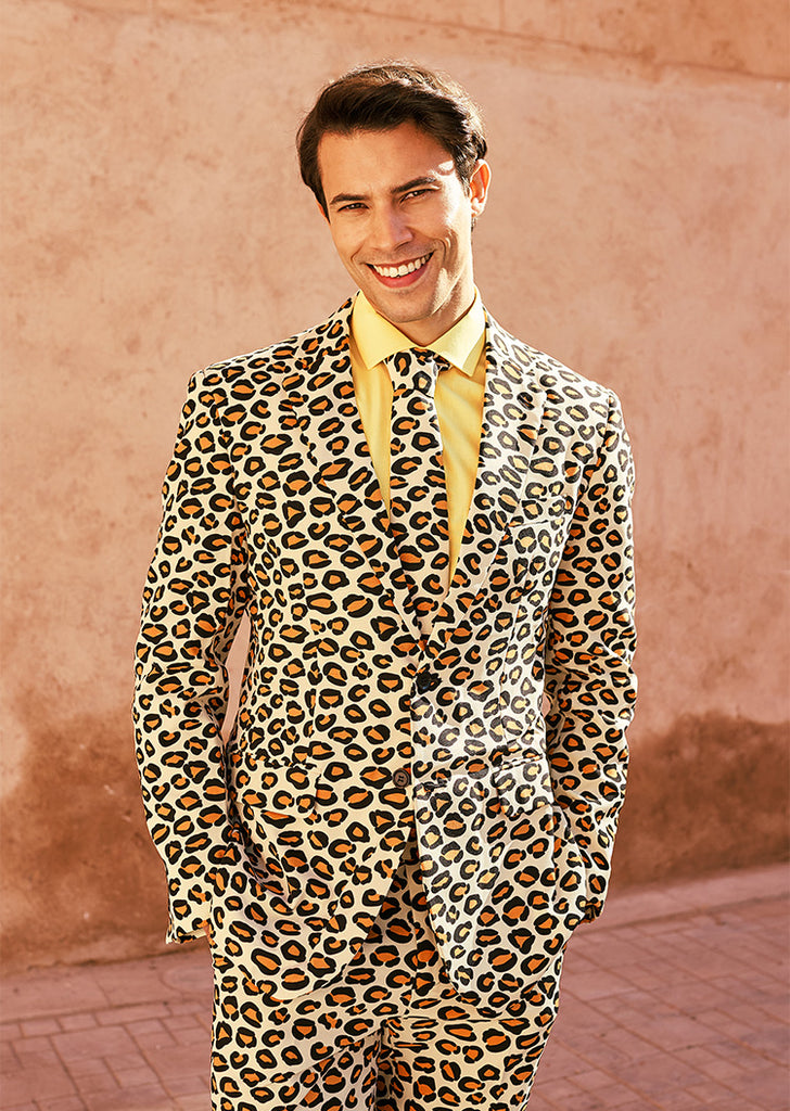 Man smilling in the camera wearing men's suit with panther print and yellow shirt.