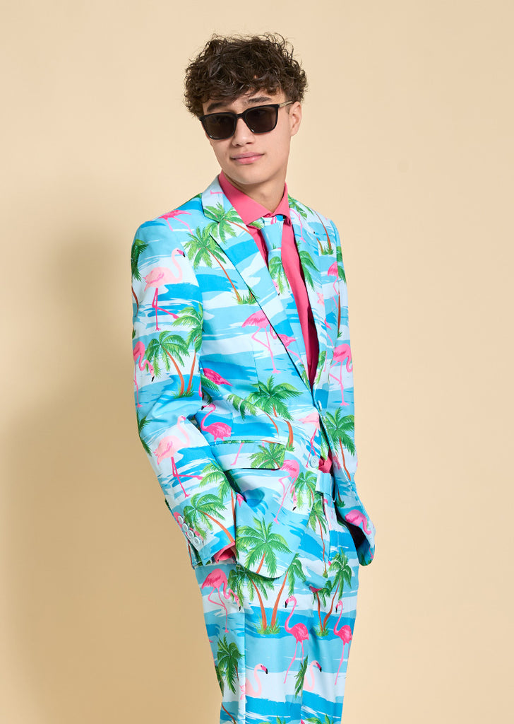 Teen wearing a light blue tropical styled suit and a pink shirt. He is also wearing sunglasses.