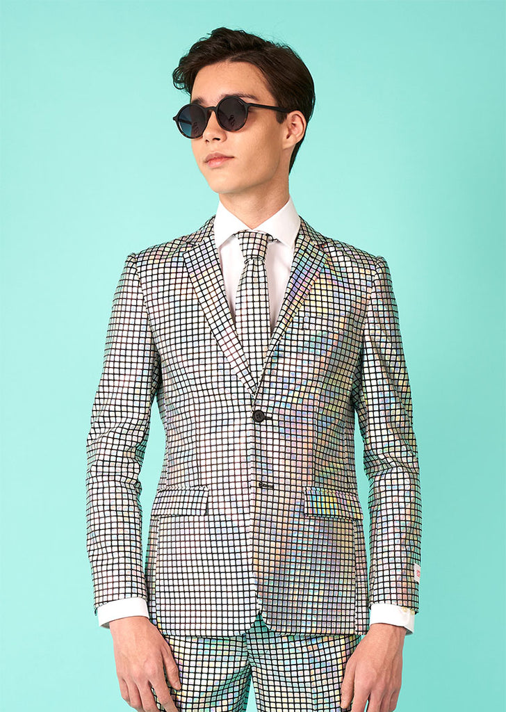 Teen standing in front a blue background wearing sunglasses and a Teen Boys suit with mirror patches. So, it looks like a discobal. 