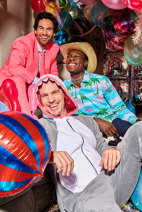 Image of 3 men partying, One man wearing a pink suit, one man wearing a tropical shirt and a man wearing a shark onesie.
