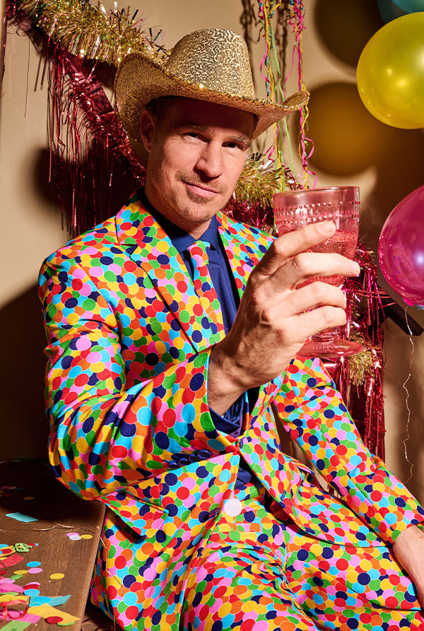 image of a man wearing a confetti suit and a hat. And he is holding a glass.