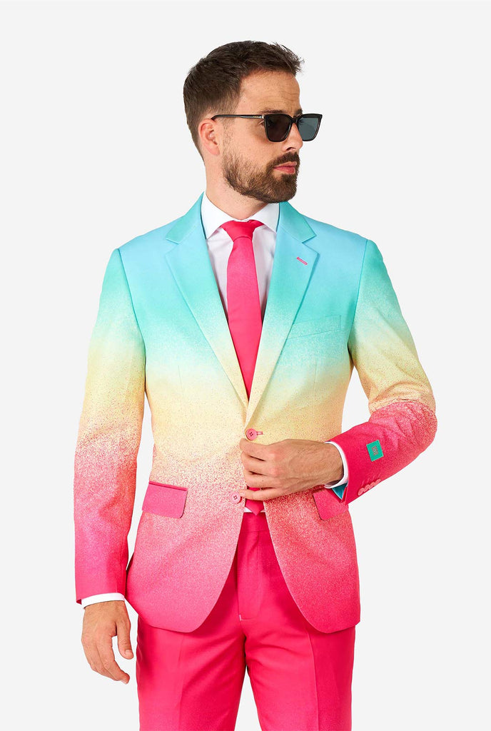 Video of man wearing Funky Fade pride men's suit, showing suit like a model. Suit consists of blazer, pant and tie.