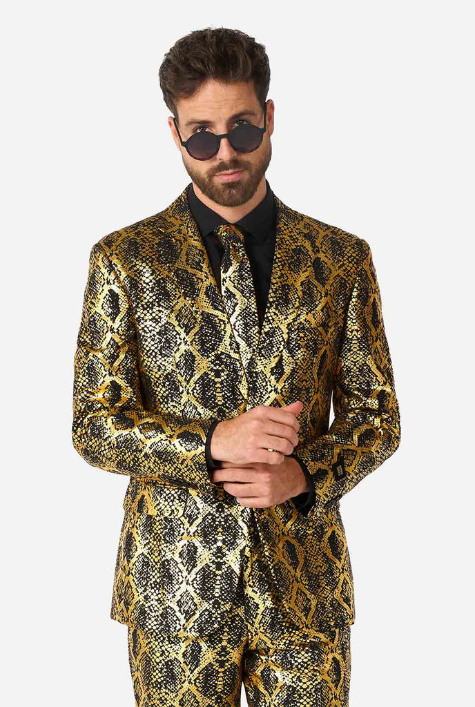 Video of man wearing Shiny Snake men's suit with golden snake skin print, showing suit like a model. Suit consists of blazer, pant and tie.