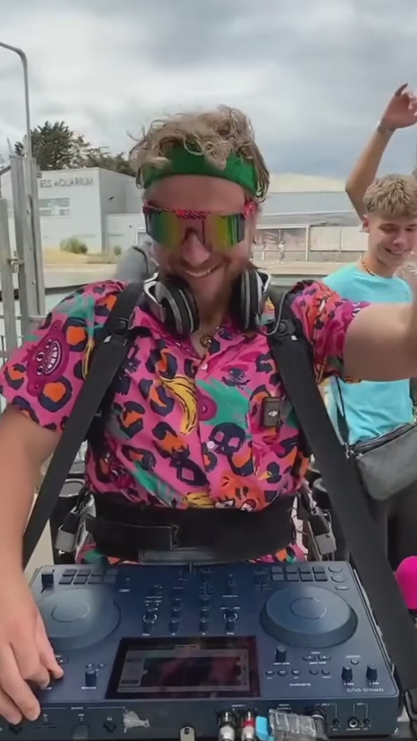 short video of a DJ walking on the street, wearing the OppoSuits Jazzy Jungle Summer Set,  with dancing people around him.